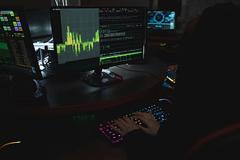 cybersecurity expert, dimly lit room, colorful keyboard, multiple screens, data display, computer use, typing, dark environment, technology workspace, professional setup, data analysis