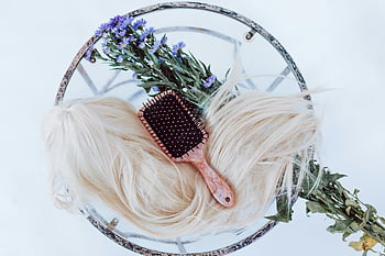 blonde wig, hair brush, purple flowers, round table, hair beauty, hair care, floral wreath, black and white brush, white and green floral, hair styling, hair accessories