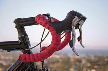 red handlebars, black road bicycle, racing bicycle, blurred background, sunset, detailed view, red and black, bicycle handlebars, road bike, cycling, sports equipment