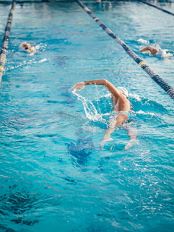 outdoor swimming pool, adult swimmer, freestyle stroke, swimming practice, pool lanes, water splashes, swimmer training, competitive swimming, outdoor pool, swimmer in action, swimming technique