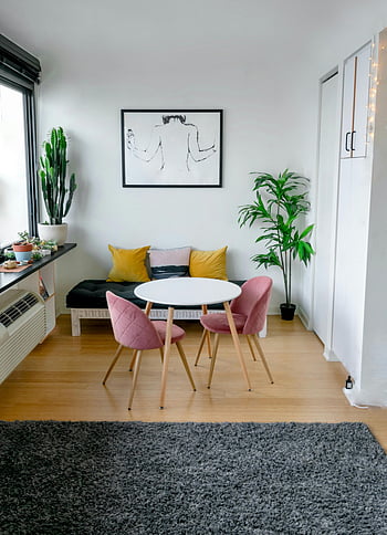 moderne stue, Stilfulde møbler, kunstværk, frodig grønt, tæppe, trægulv, lyserøde stole, hvidt bord, moderne indretning, indendørs planter, hyggeligt interiør