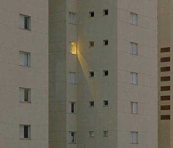 modern apartment building, white concrete building, glass windows, lit window, night facade, striking focal point, urban architecture, contemporary design, building exterior, night photography, architectural photography