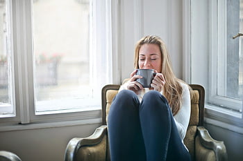 žena hospodářství hrnek, Útulné křeslo, teplý nápoj, relaxace, šedý keramický hrnek, zobrazení okna, vnitřní pohodlí, klidný okamžik, Domácí volný čas, klidná atmosféra, Žena si užívá kávu