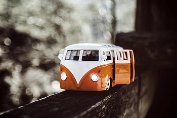White Orange Van, scale model, vintage toy, campervan, wooden beam, bokeh background, close-up, toy vehicle, miniature car, retro design, classic van