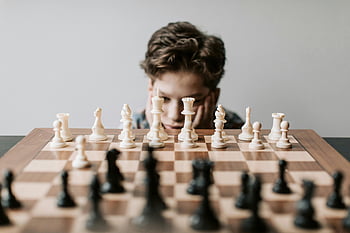 boy playing chess, young boy chess, chessboard, strategic move, indoor chess, focused boy, chess pieces, chess game, indoor game, boy chess player, chess strategy