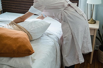 housekeeper, putting pillowcase, pillow, tidying bedroom, adjusting linens, neat appearance, hotel room, bed making, housekeeping service, hotel staff, bedroom tidying