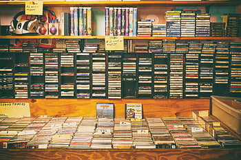 fitas cassete, cds, loja de discos vintage, caixas rotuladas, exibição nostálgica, prateleiras, coleção de músicas, trilhas sonoras, música vintage, mídia de áudio, loja retrô