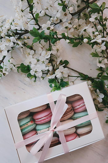 assorted-color cookies, macarons, charming box, ribbon, white cherry blossoms, table, assorted macarons, gift box, pink ribbon, floral arrangement, dessert presentation