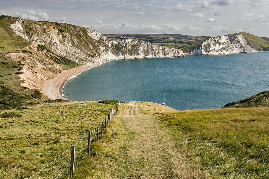 coastal bay, cliffs, grasslands, clear blue waters, breathtaking view, island field, green grass, beach, landscape, natural scenery, seaside view