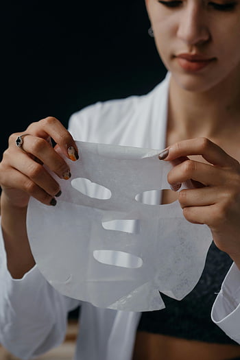 obličejová maska, péče o pleť, zvlhčující listová maska, žena drží masku, Detailní péče o pleť, kosmetické ošetření, péče o obličej, Aplikace masky listu, Rutina krásy, Zaměření na péči o pleť