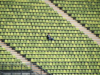 nő szürke ingben, stadion szék, zöld és sárga ülések, magányos alak, München Németország, stadion magány, üres stadion, zöld ülések, sárga ülések, stadion ülések, magányos pillanat
