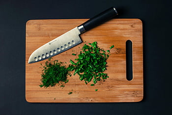 silver kitchen knife, cutting board, chopped herbs, kitchen utensil, culinary tool, black handle knife, stainless steel blade, food preparation, kitchenware, herb chopping, wooden cutting board