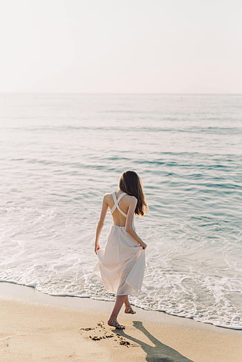 woman in white dress, walking on beach, barefoot, sandy beach, serene summer day, by the sea, ocean waves, coastal scene, beach walk, woman enjoying beach, white dress on beach