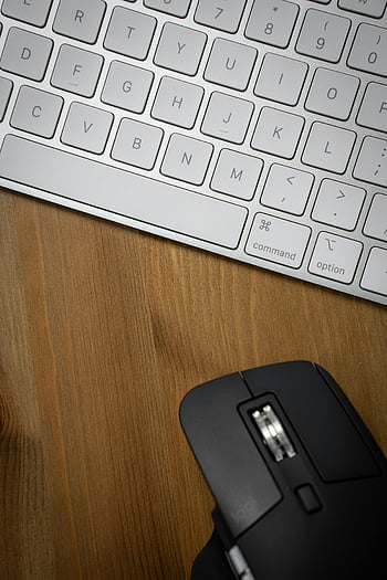 black computer mouse, white keyboard, ergonomic mouse, wooden surface, sleek workspace, workspace setup, black mouse, white computer keyboard, desk setup, office equipment, computer peripherals