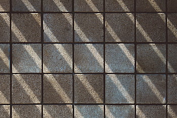 brown concrete floor tiles, sunlit shadows, geometric pattern, textured gray tiles, abstract appeal, minimalistic design, floor texture, shadow play, modern flooring, architectural detail, indoor design