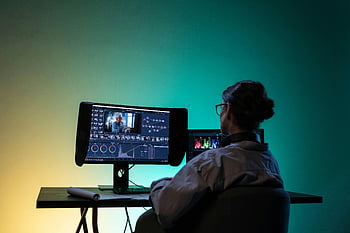 female editor, computer, video editing, color correction, dimly lit room, backview, workspace, professional editing, digital editing, creative work, technology
