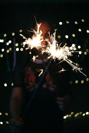 bokeh photography, woman holding sparklers, night scene, bokeh lights, dark background, sparklers, festive atmosphere, outdoor celebration, night celebration, bokeh effect, sparkler photography
