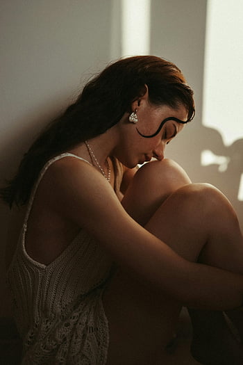 woman in sunlight, thoughtful woman, sitting by window, serene introspection, natural light, portrait of woman, calm atmosphere, indoor setting, contemplative mood, soft lighting, peaceful scene