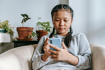 etnické dívka, chytrý telefon, útulný obývací pokoj, mladá dívka, copánky, zaměřené, Vnitřní nastavení, neformální oblečení, Domácí prostředí, hrnkové rostliny, uvolněná atmosféra