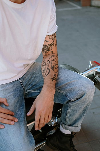 Homme en chemise blanche, jeans, tatouages ​​au bras, assis sur une moto, Style décontracté, cadre extérieur, scène urbaine, motard, bras tatoué, Tenue décontractée, style de rue