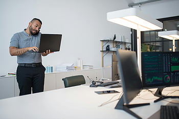 mężczyzna wykonujący wiele zadań jednocześnie, smartfon, laptop, nowoczesne biuro, konfiguracja wielozadaniowości, połączenie telefoniczne, biurko, monitory komputerowe, Profesjonalny obszar roboczy, środowisko pracy, wykorzystanie technologii