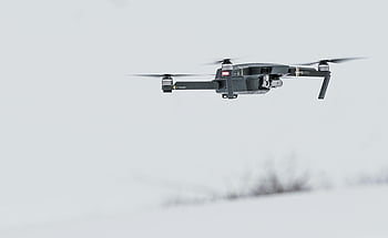 Black Drone, modern drone, snow-covered setting, advanced technology, flying drone, serene landscape, winter scene, aerial photography, drone technology, snowy environment, unmanned aerial vehicle
