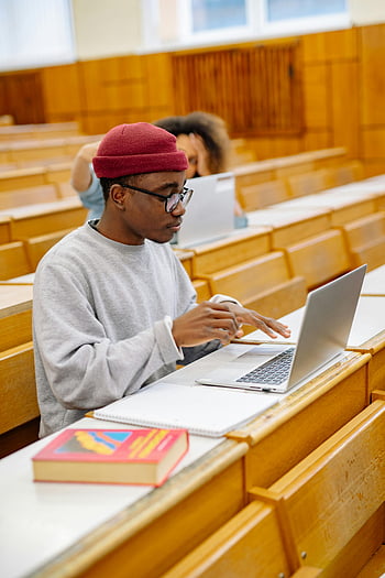 student using laptop, lecture hall, focused student, studying, taking notes, classroom, educational setting, academic environment, student life, learning, books