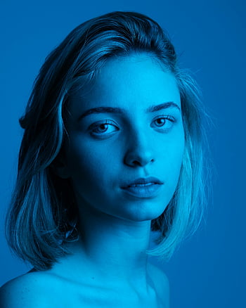 portrait, young woman, blue light background, artistic headshot, calm expression, blue-toned, female portrait, studio photography, blue background, headshot, calm face