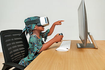 child learning technology, VR headset, young child, technology engagement, desk setup, controller use, virtual reality, educational tech, interactive learning, computer desk, child technology