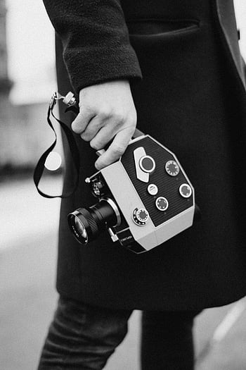 fotografie ve stupních šedi, osoba držící fotoaparát, Retro filmová kamera, černobílé fotografování, nadčasové okamžiky, Černý a bílý, vinobraní fotoaparát, pouliční fotografie, analogové fotografie, klasický fotoaparát, ruční kamera