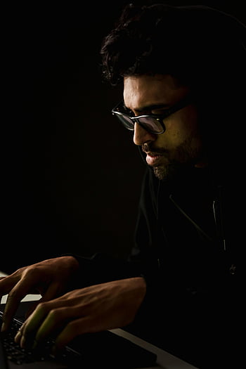 nerd informatico etnico, digitando sulla tastiera, crepuscolo, stanza buia, digitando attentamente, il computer portatile, tecnologia informatica, temi, uomo, bicchieri, felpa con cappuccio