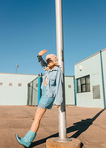 žena opírající se o pouliční lampu, Stylový model, džínové oblečení, Modré boty, pózování u tyče, des moines, jasné modré nebe, městské módy, pouliční styl, blond vlasy, Příležitostná elegance