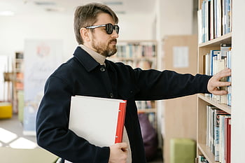 視覚障害のある男性、 本棚、 としょうかん、 アクセシビリティ、 リテラシー、 感動的な本、 男が探検している、 視覚障害、 図書館のアクセシビリティ、 識字率向上