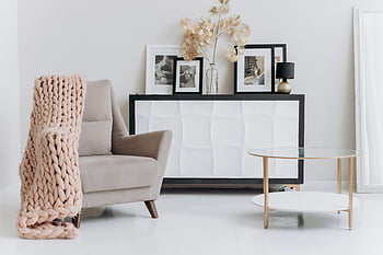 beige sofa chair, near table, cozy interior, contemporary setup, soft decor, elegant furnishings, beige chair, white console table, modern living room, pink blanket, framed pictures
