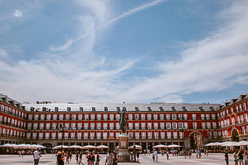 Plaza Mayor, Madrid, tourists, vibrant blue sky, scenic view, historic building, outdoor square, city landmark, travel destination, European architecture, sunny day