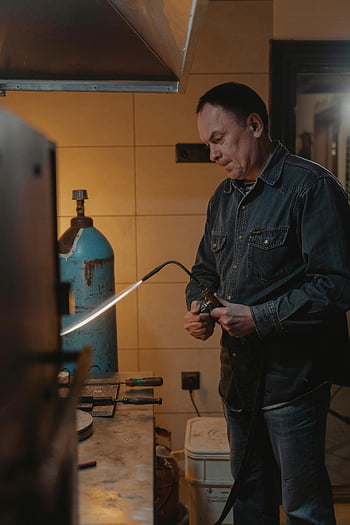 férfi állítja be a lángszórót, kézműves, beltéri műhely, farmeröltözék, blowtorch, műhely eszközök, ipari környezetben, ember dolgozik, craftsperson, műhelykörnyezet, gázpalack