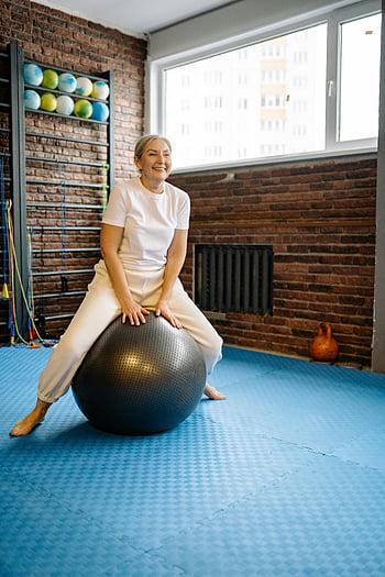 elderly woman, wellness ball, senior exercise, stability ball, gym setting, active lifestyle, indoor fitness, senior fitness, exercise ball, healthy aging, gym equipment