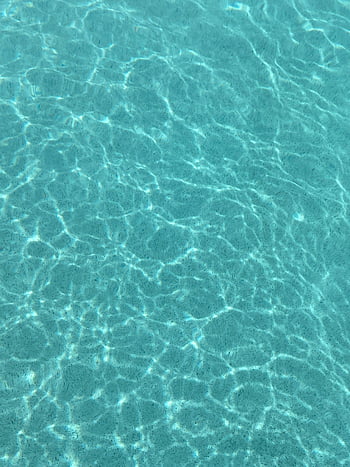 sun reflection, pool, clear blue water, sunlight, serene swimming pool, calming effect, water ripples, pool surface, tranquil water, outdoor pool, summer vibe