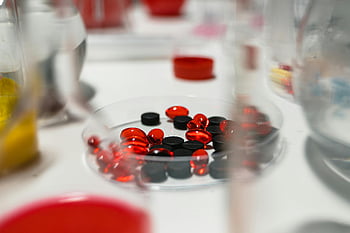 comprimés rouges et noirs, photo en gros plan, table de laboratoire, arrière-plan flou, pilules rouges, pilules noires, vue rapprochée, équipement médical, cadre de laboratoire, médicaments, des médicaments