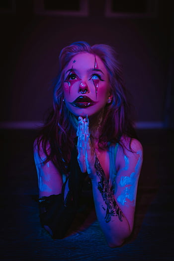 woman in clown costume, clown makeup, spooky atmosphere, mysterious portrait, darkness, neon lighting, haunting image, tattooed woman, eerie scene, creepy clown, neon colors