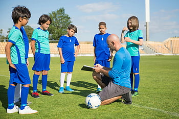 entraîneur de football, jeunes joueurs de football, champ vert luxuriant, ciel clair, t-shirt bleu, terrain de football, foot enfants, coaching sportif, sports de plein air, sports pour les jeunes, Entraînement de football