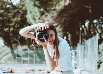 γυναίκα που φωτογραφίζει, dslr κάμερα, εξωτερική ρύθμιση, χαμογελαστή γυναίκα, φωτογραφία, φόντο της φύσης, casual ενδυμασία, ημέρα, πάρκο σκηνή, ειλικρινής στιγμή