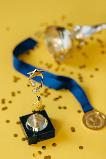 Goldene Trophäe, Medaille, gelbes Konfetti, blaues Band, vergeben, Feier, Nahansicht, goldene Medaille, Trophäe und Medaille, mit Konfetti übersäte Oberfläche, Sieg
