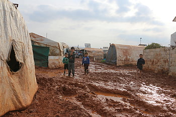 uprchlický tábor, Idlib Sýrie, etnické děti, ošuntělé stany, Muddy cesty, Děti navigují, uprchlické děti, Humanitární krize, přemístění, stanové město, podmínky chudoby