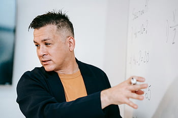 male teacher, mathematical concepts, whiteboard, classroom setting, explaining, education, teaching, math, lecture, chalkboard, instruction