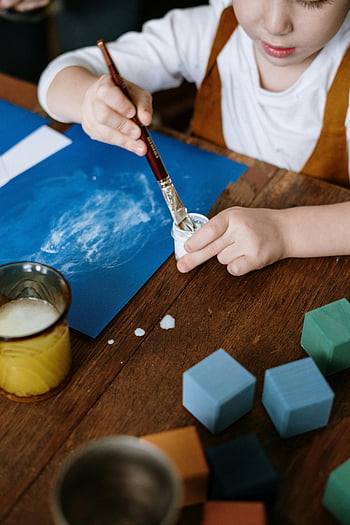 小さな男の子の絵、 幼い子供の絵、 アートセッション、 創造性を探求する、 さまざまな素材、 絵筆、 木製テーブル、 カラフルなブロック、 ブルーペーパー、 画材、 創造的な活動