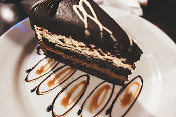 sliced cake, chocolate mousse cake, caramel drizzle, chocolate drizzle, white plate, close-up, dessert, cake slice, mousse cake, caramel sauce, chocolate cake