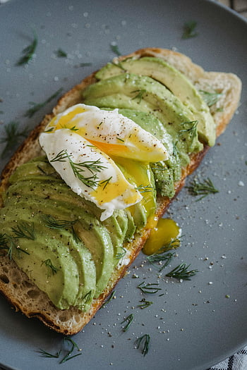 Toast all'avocado, uovo in camicia, avocado affettato, erbe aromatiche, prima colazione, cibo salutare, Panino all'avocado, toast con l'uovo, fotografia di cibo, pasto vegetariano, panino colazione