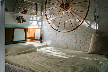 cozy bedroom, vintage decor, wagon wheel accent, soft natural lighting, brick wall, interior design, rustic bedroom, home decor, wall art, cozy interior, vintage bedroom