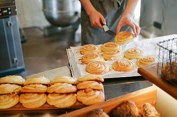 cinnamon rolls, bakery, preparing bread, tray, cozy setting, delicious pastries, person baking, fresh bread, bakery interior, bread preparation, cinnamon swirls